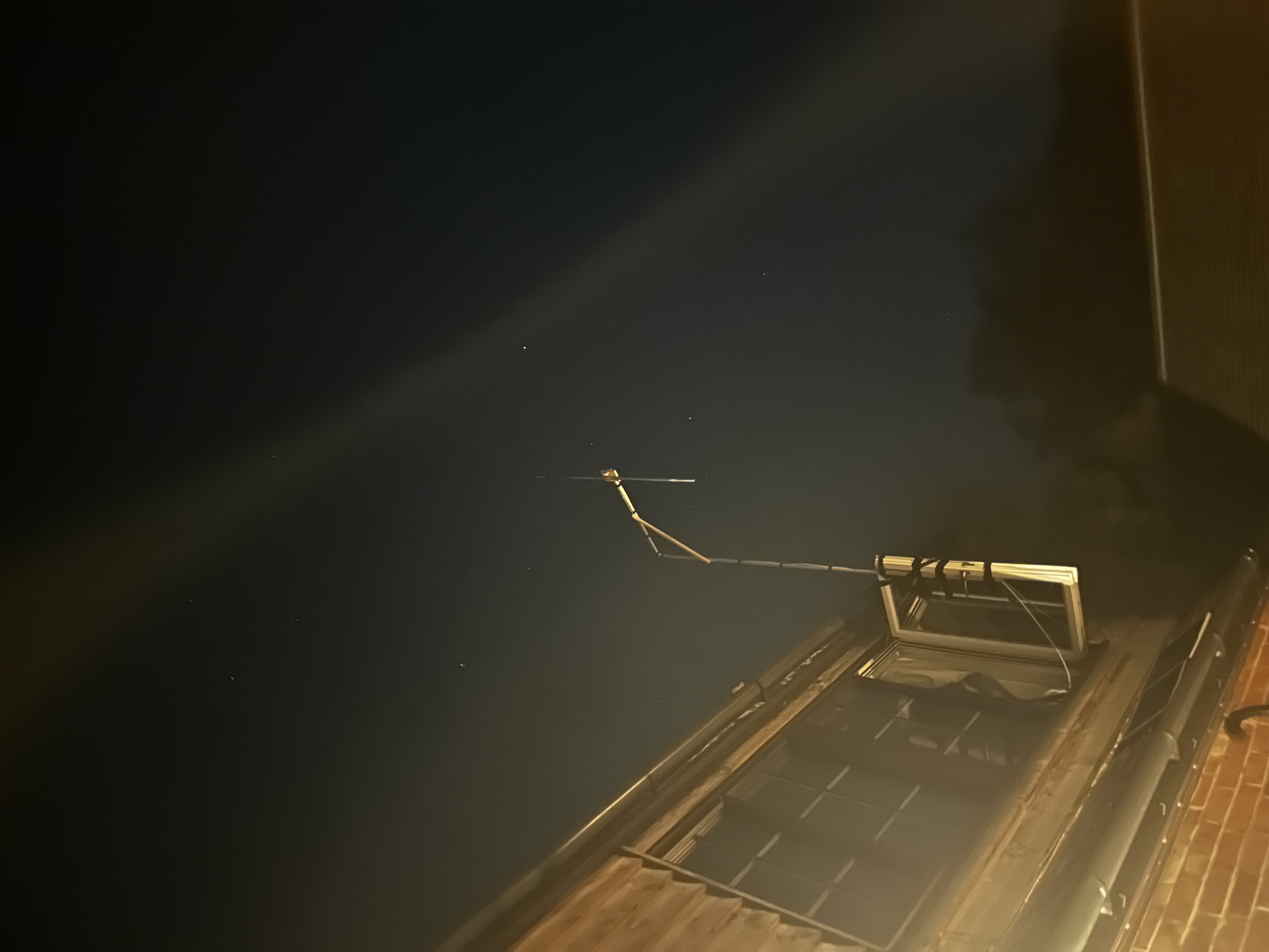 An outdoor antenna mounted near a window at night